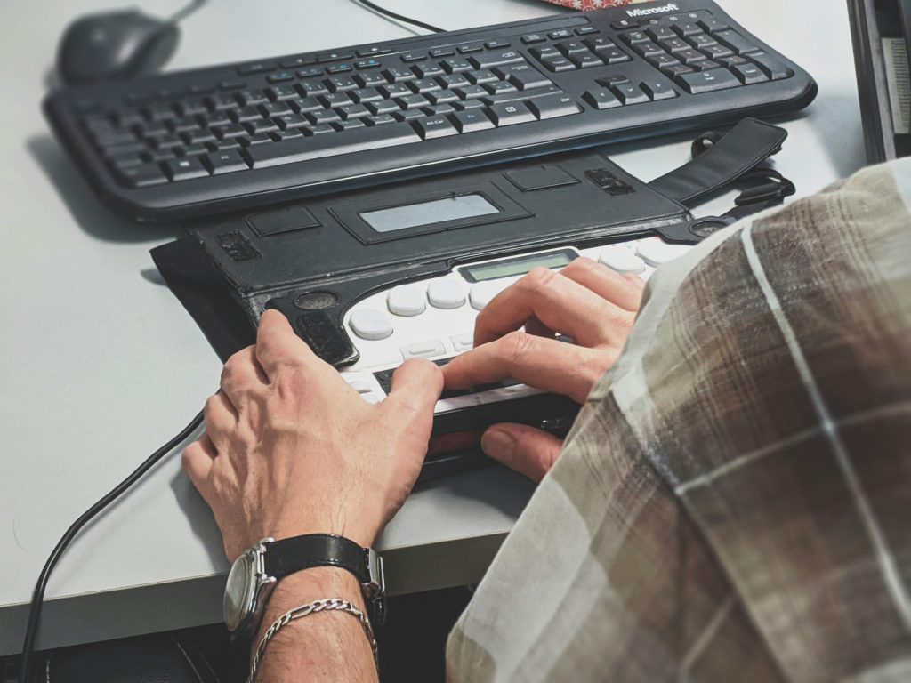 Persoană nevăzătoare care citește un site pe un afișaj braille conectat la laptop.