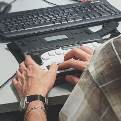 Persoană nevăzătoare care citește un site pe un afișaj braille conectat la laptop. Persoană nevăzătoare care citește un site pe un afișaj braille conectat la laptop.
